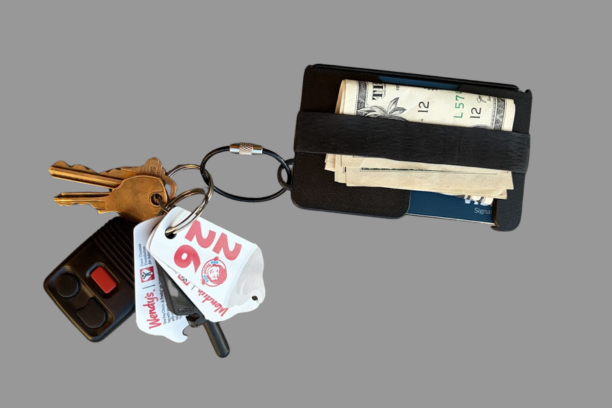 The Metal Brik wallet holding cash, with keys attached to the integrated keyring